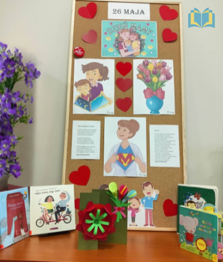 Zdjęcie: Gazetka z okazji Dnia Mamy. Kolorowe zdjęcia kwiatów i mam. W środku czerwone serca. Obok gazetki wystawka książek.